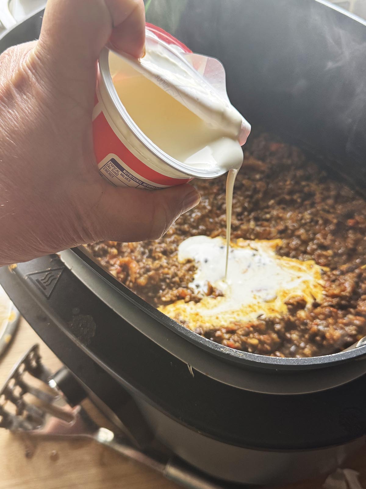 Adding cream to the dal makhani.