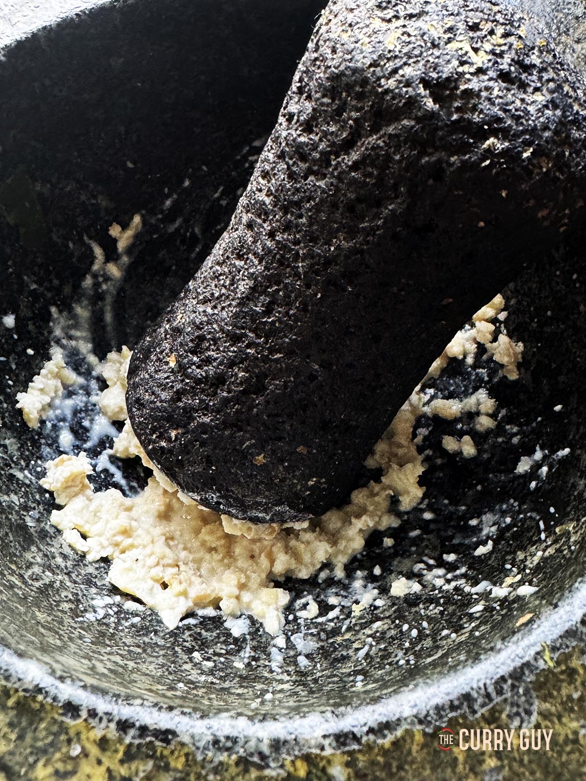 Smashing cashews in a pestle and mortar into a paste.