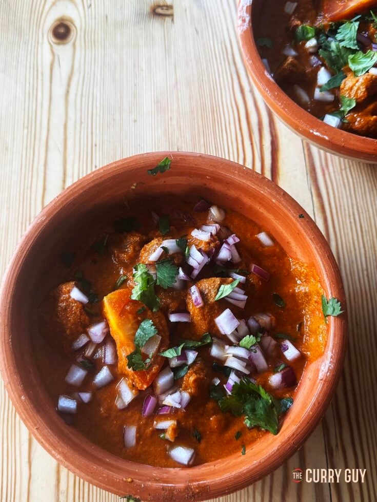 Two serving bowls filled with slow cooker rogan josh