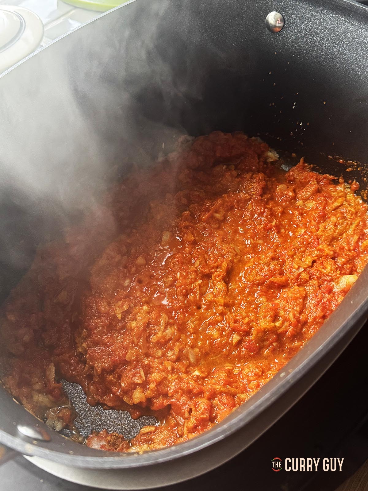 Adding the chopped tomatoes and stock to the pan.