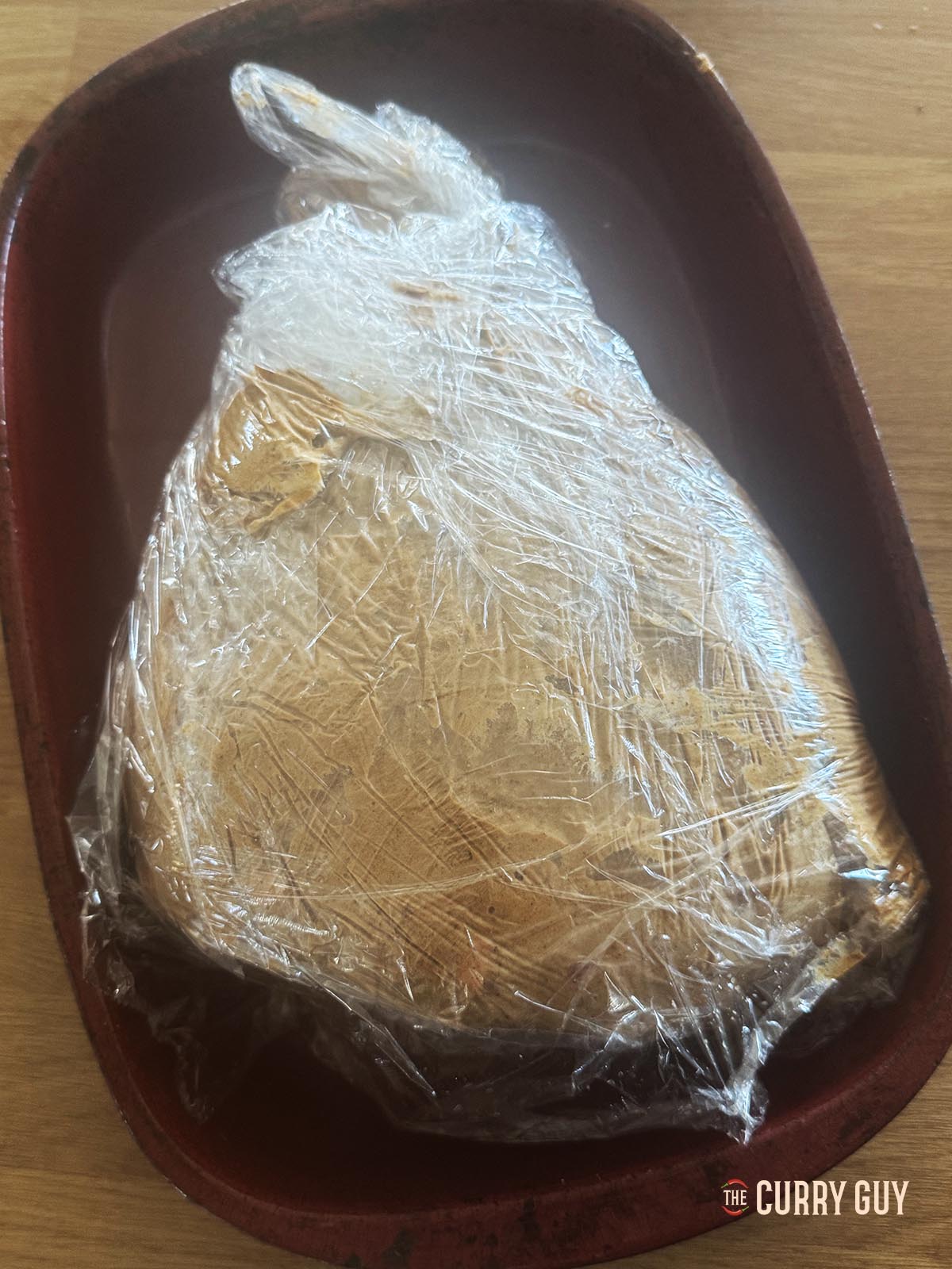 The lamb leg wrapped in plastic wrap marinating.