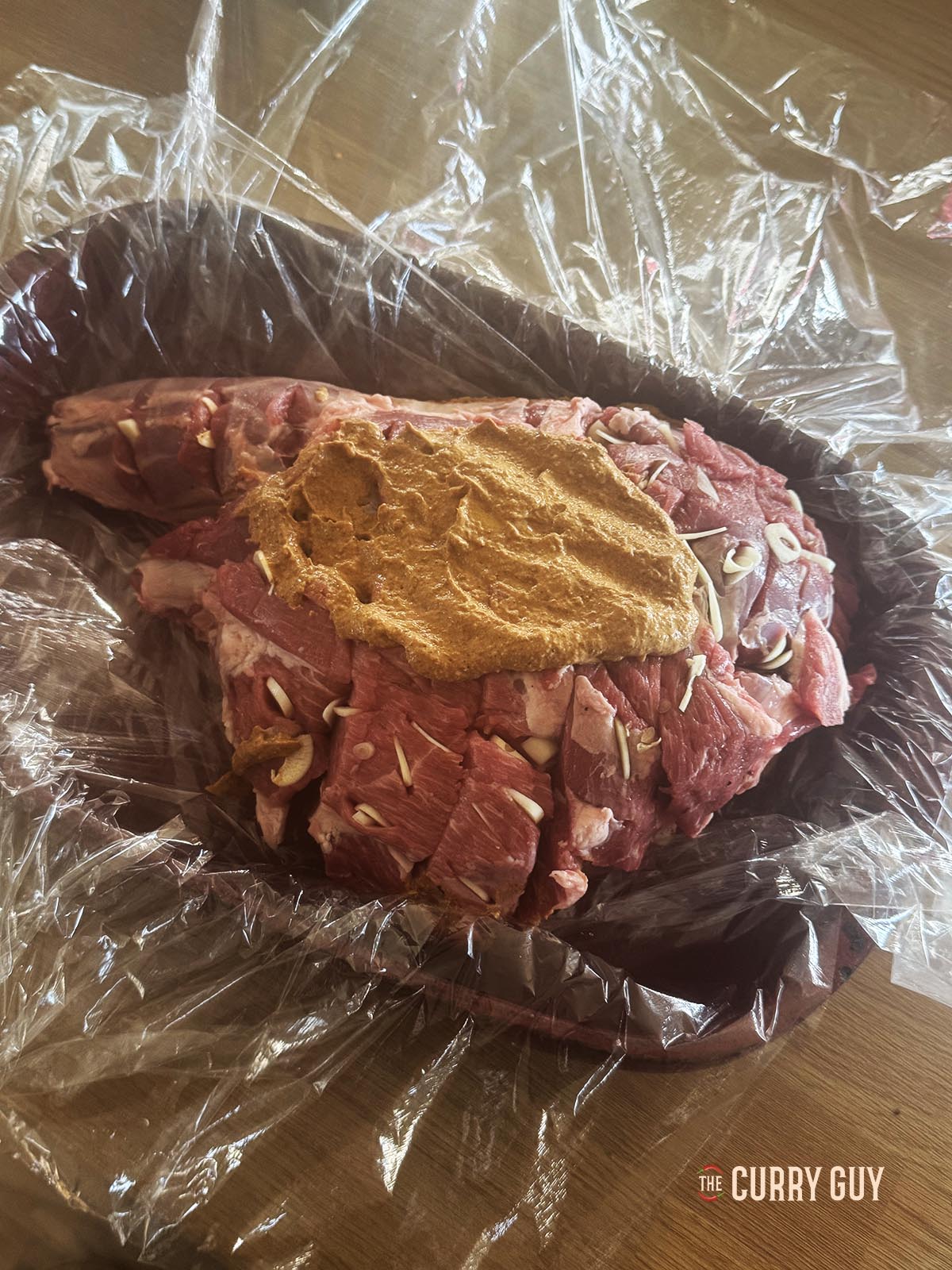 Adding the marinade to the leg of lamb.