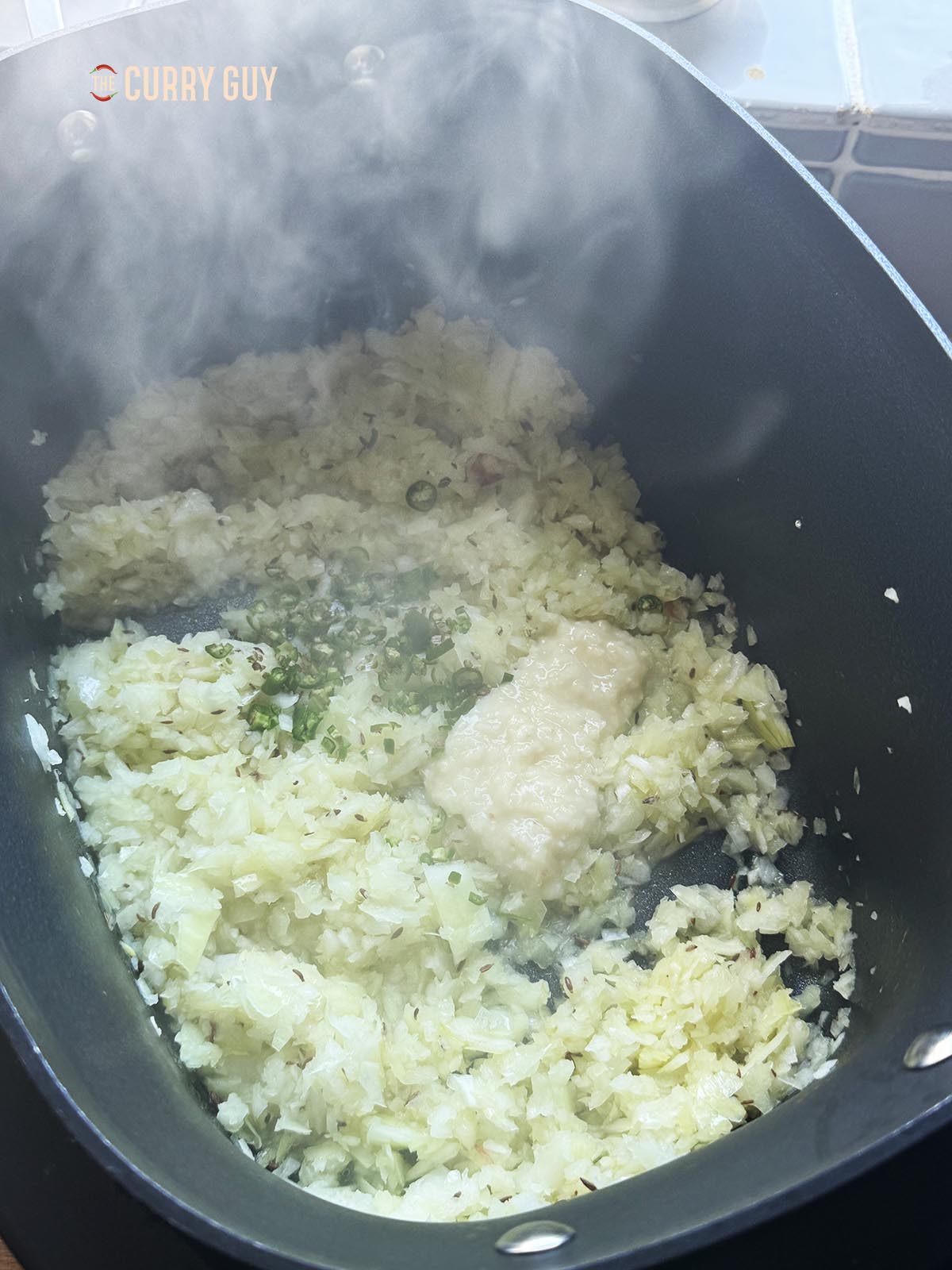Stirring the garlic and ginger paste into the onion mixture.