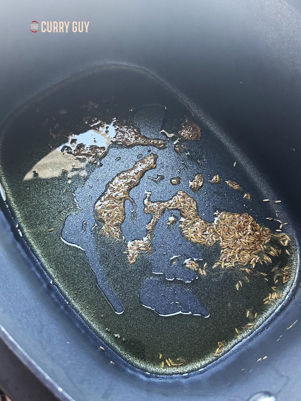 Infusing the cumin seeds into oil in the slow cooker using the sauté function.