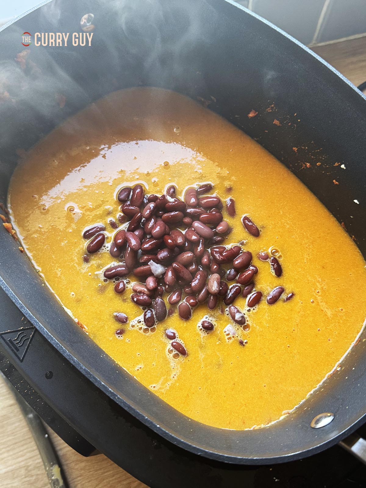 Adding the water and boiled kidney beans to the slow cooker.