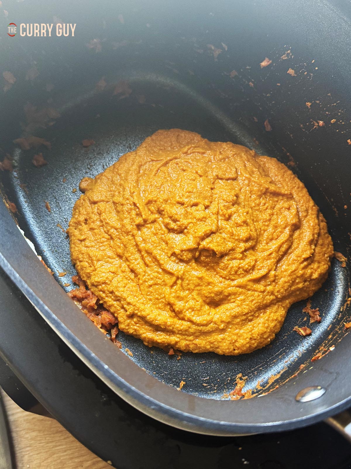 Adding the blended onion paste back into the slow cooker.