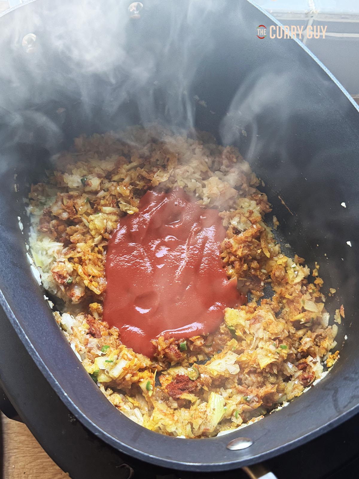 Adding the passata and tomato paste to the onion mixture.