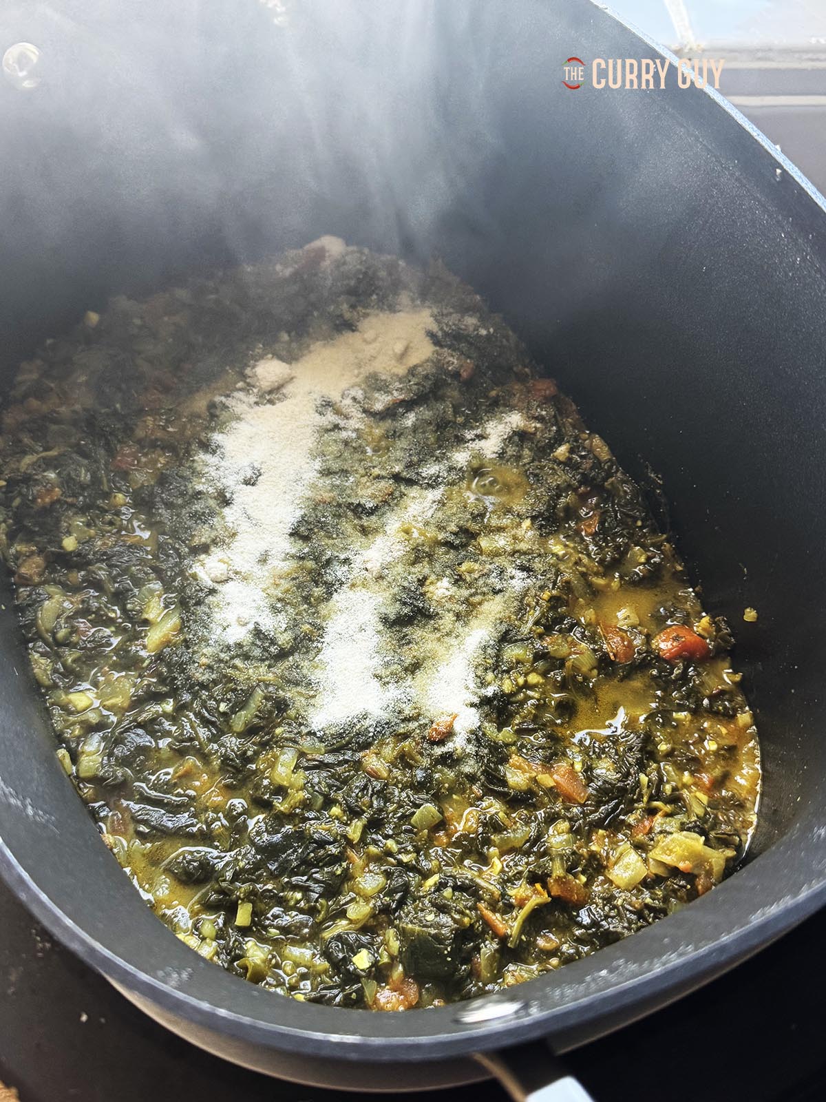 Adding the fine cornmeal to the spinach after two hours of slow cooking.