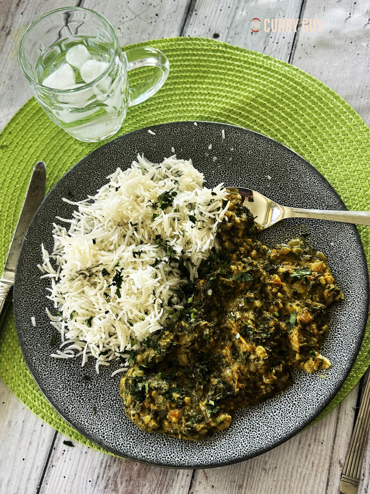 The slow cooker saag served on a plate with white rice.