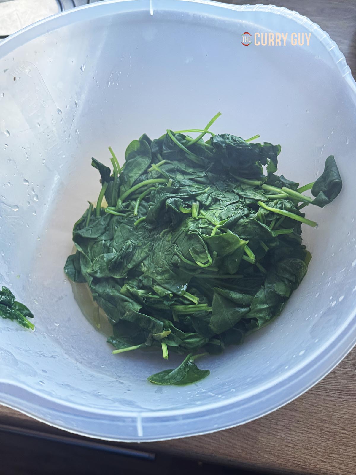 Transferring the blanched spinach to a bowl.