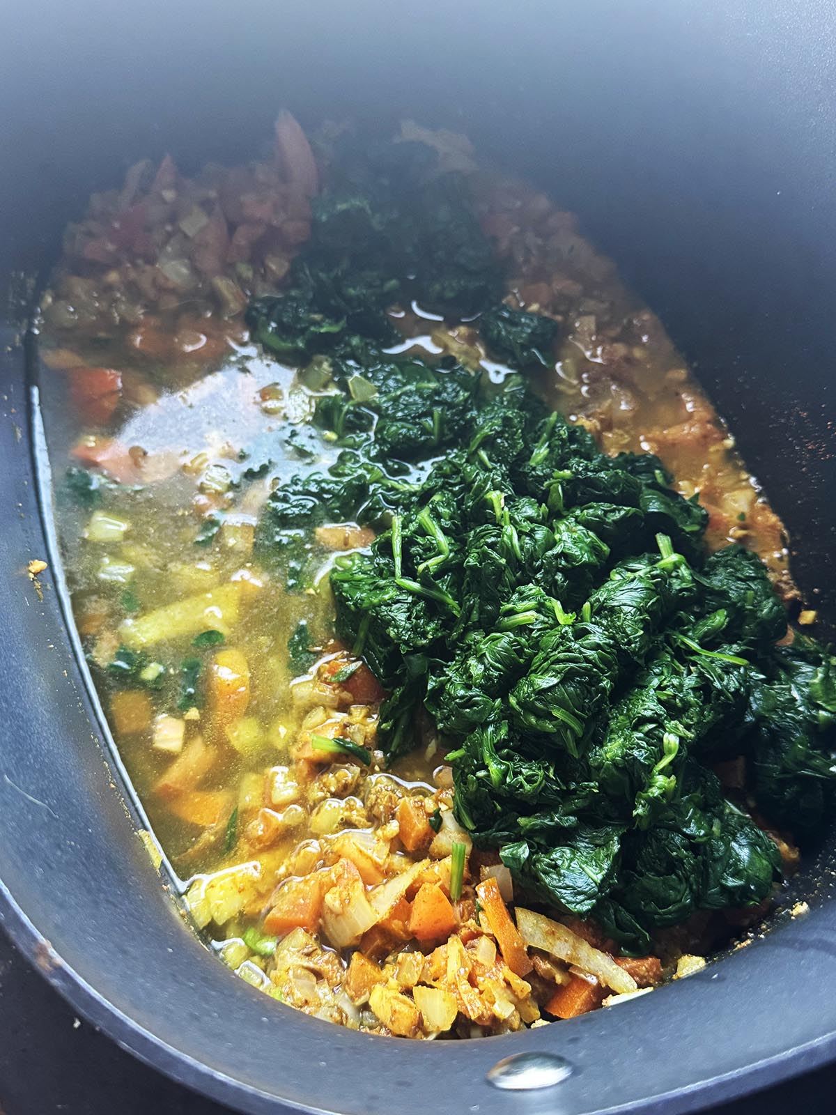 Adding the blanched and roughly chopped greens to the onion mixture with 300ml (1 1/4 cups) water