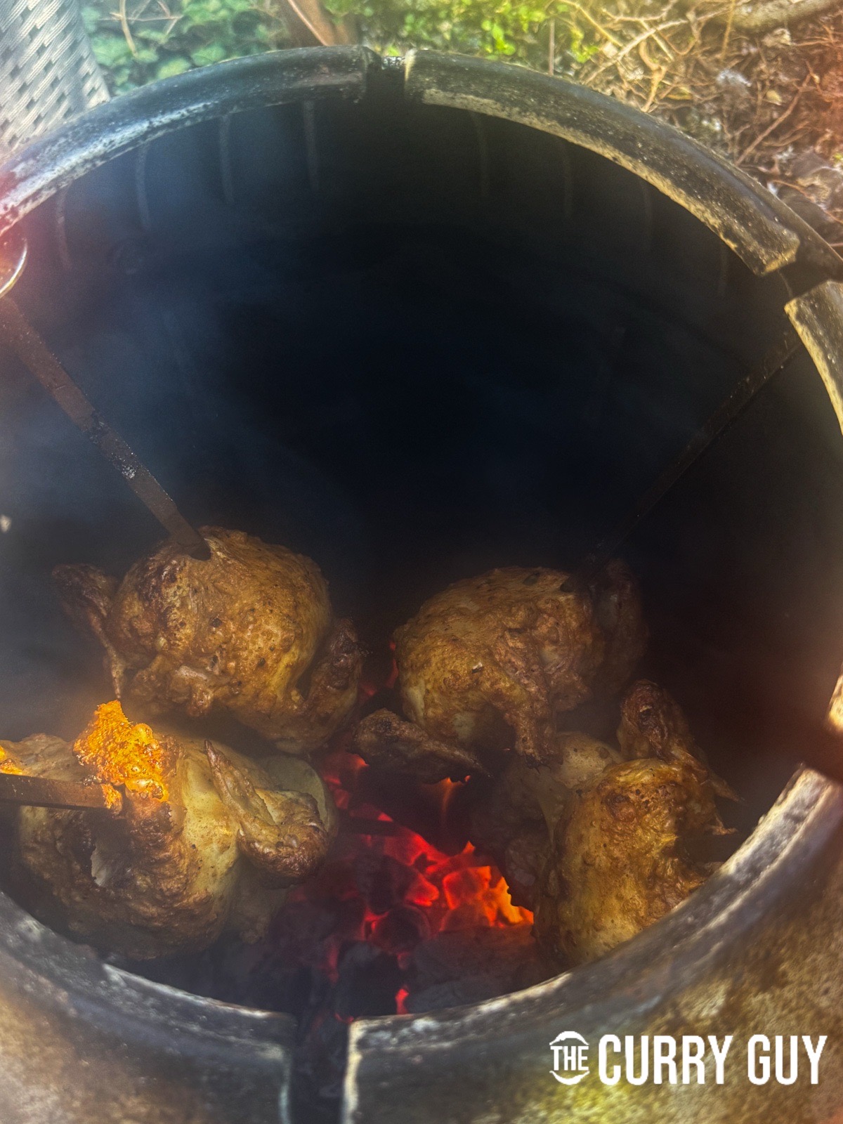 Placing the skewered chickens back into the tandoori to continue cooking.