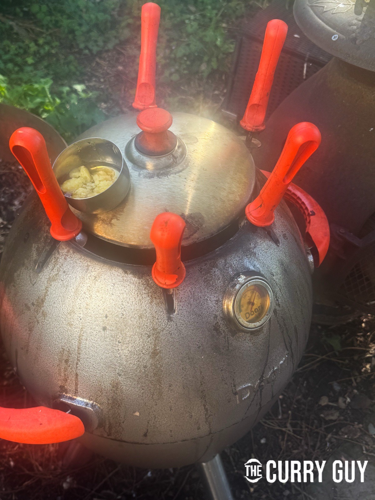 Placing a metal tin with the honey and ghee inside to melt on top of the tandoori.