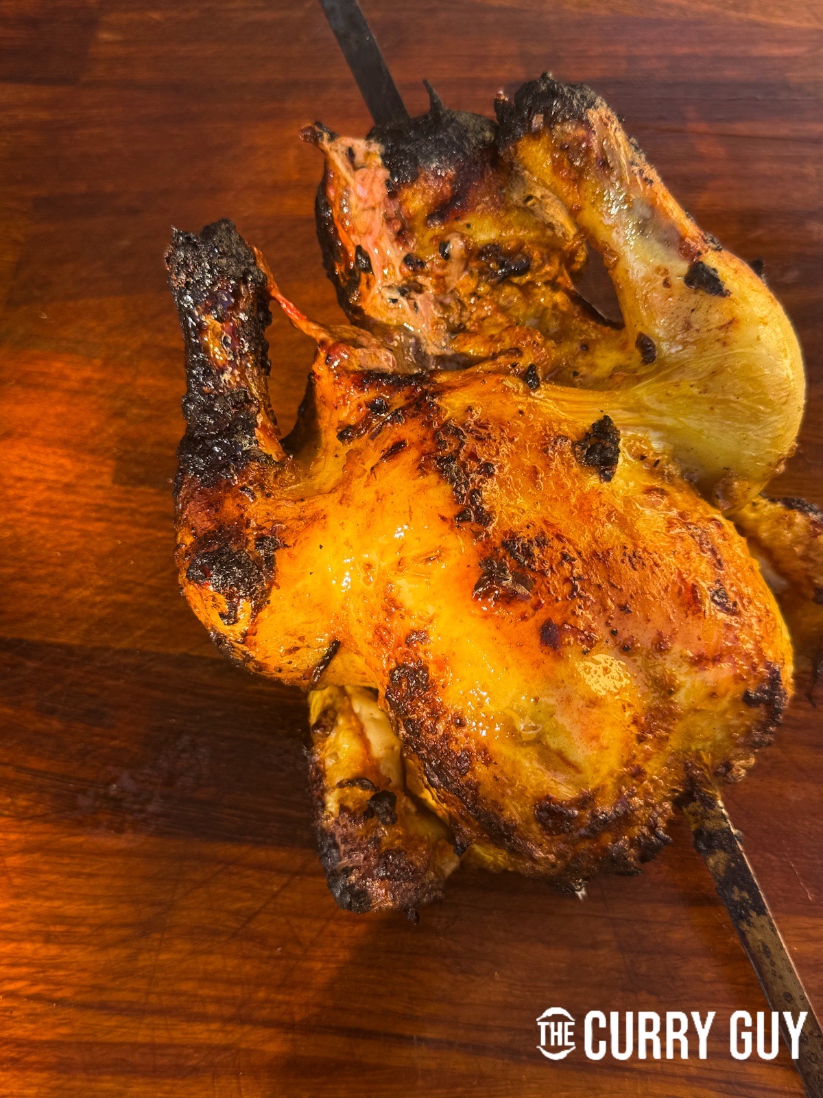 A skewered chicken resting on a cutting board.