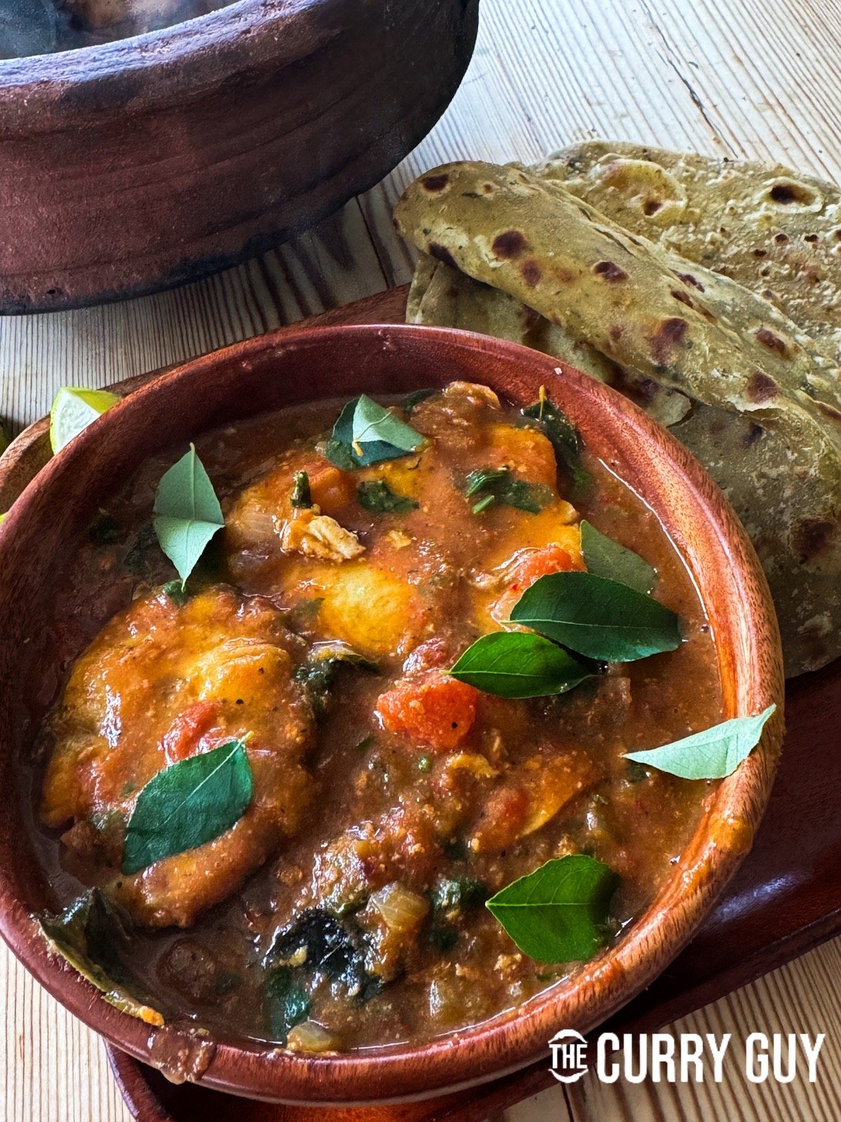 The Goan fish curry served in a bowl, garnished with curry leaves and more coriander. 