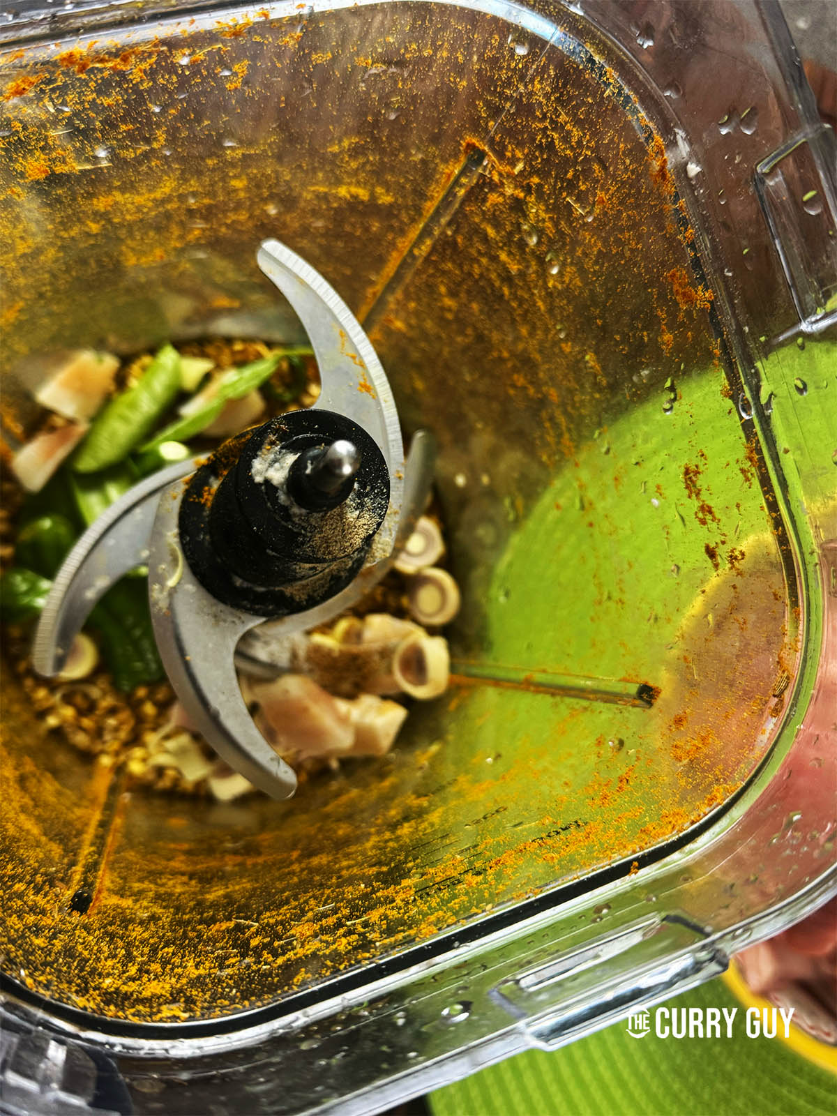 Adding the aromatics to the spice grinder to grind into a paste with the spices.