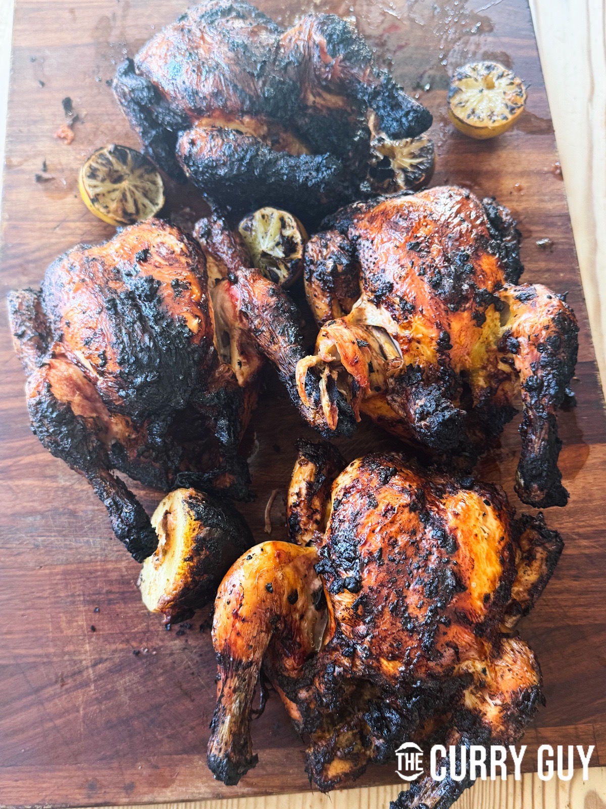 Honey roasted chicken on a cutting board with roasted limes.