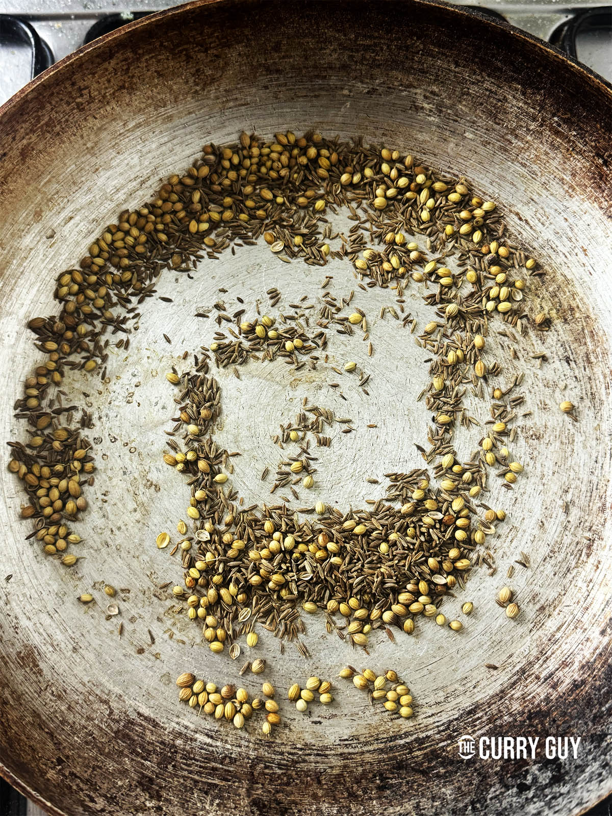 Toasting the cumin and coriander seeds in a pan.