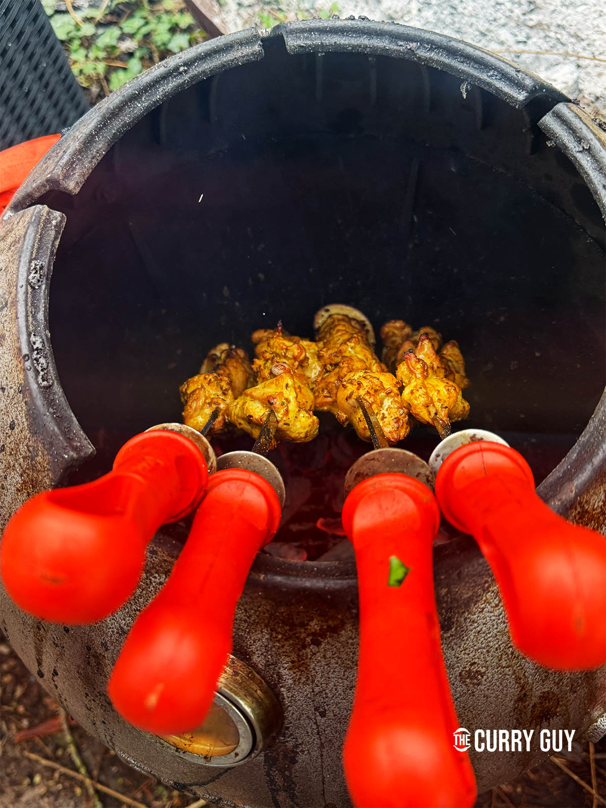 The chicken skewers charring in a tandoor oven.