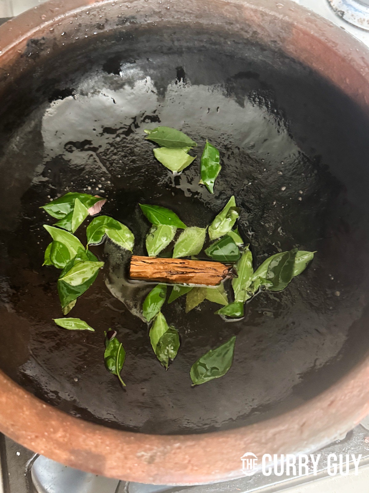 Infusing the curry leaves and cinnamon stick into the oil in the pot.