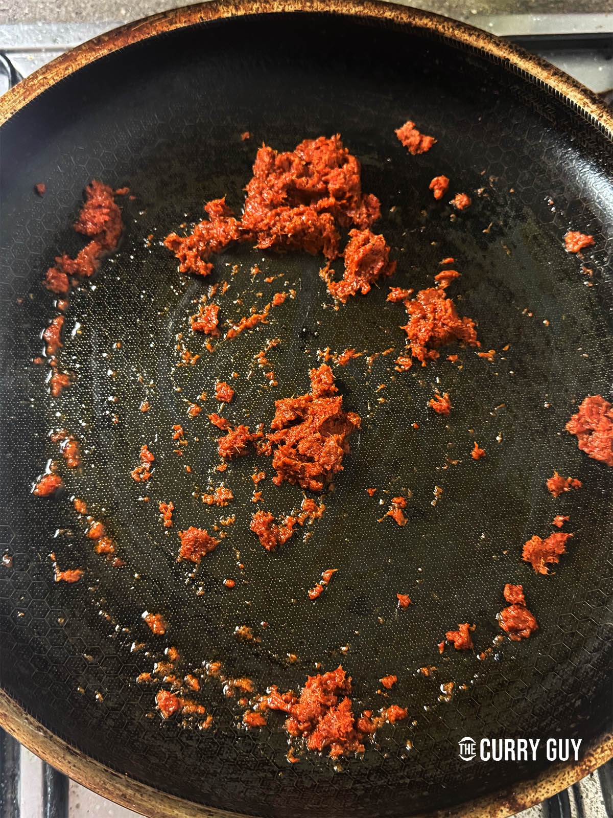 Frying 2 tablespoons of Thai red curry paste in a pan.
