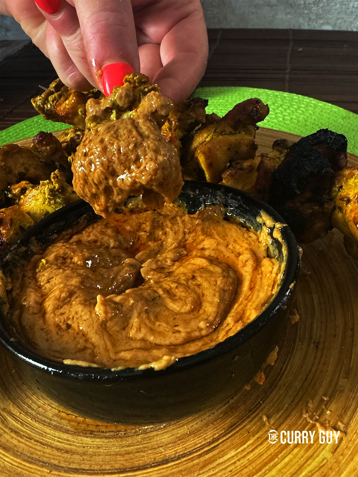 Dipping a piece of chicken into the Thai peanut sauce.