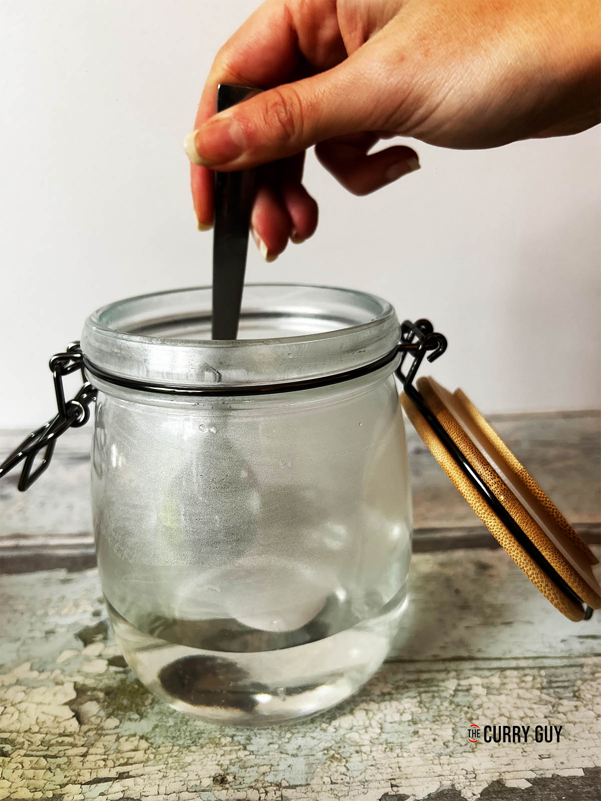 Stirring the sugar and vinegar and water together in a jar.