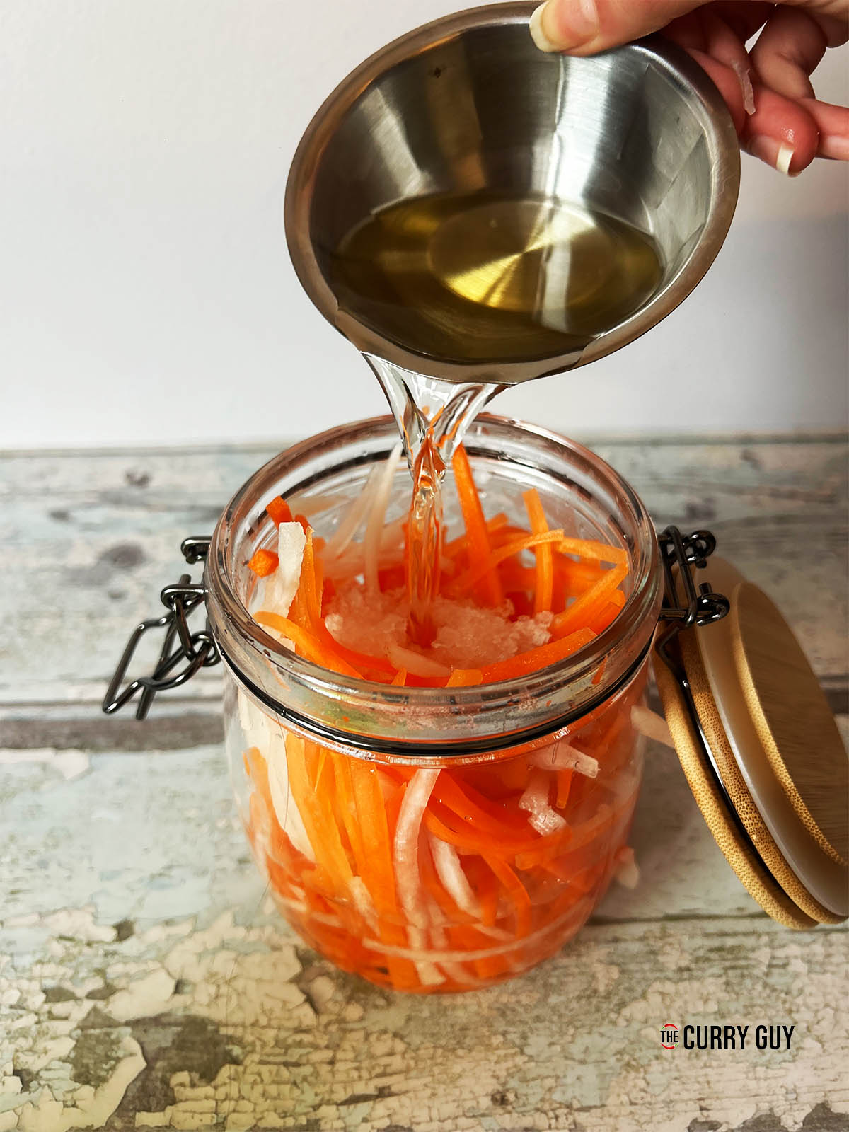 Pouring the liquid over the carrots and daikon.