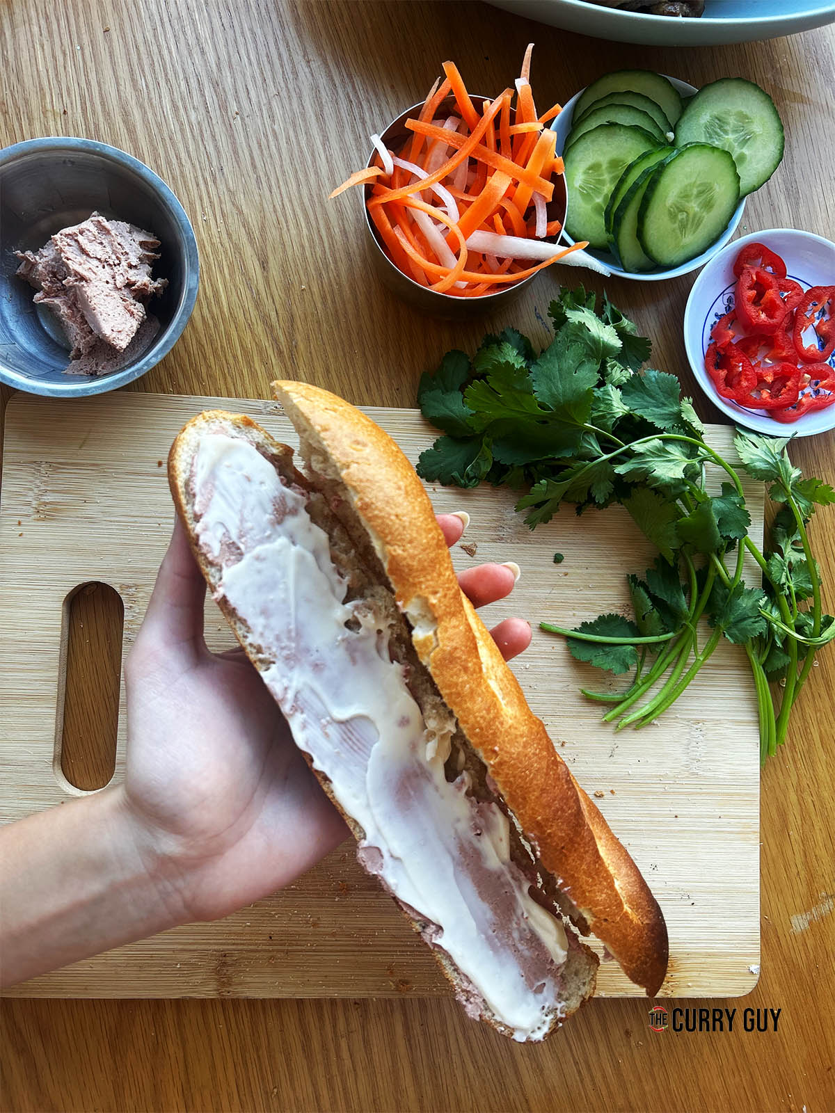 Spreading mayonnaise and pate on the bottom of the baguette.