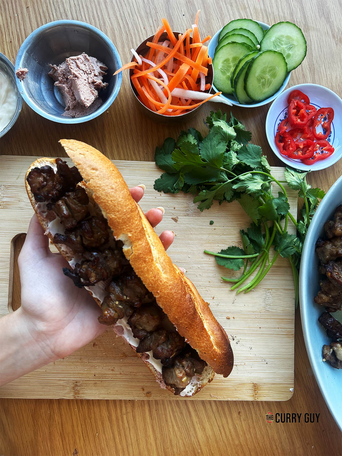 Adding the cooked pork to the baguette.