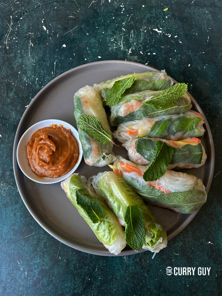 Summer rolls on a plate with peanut dipping sauce.