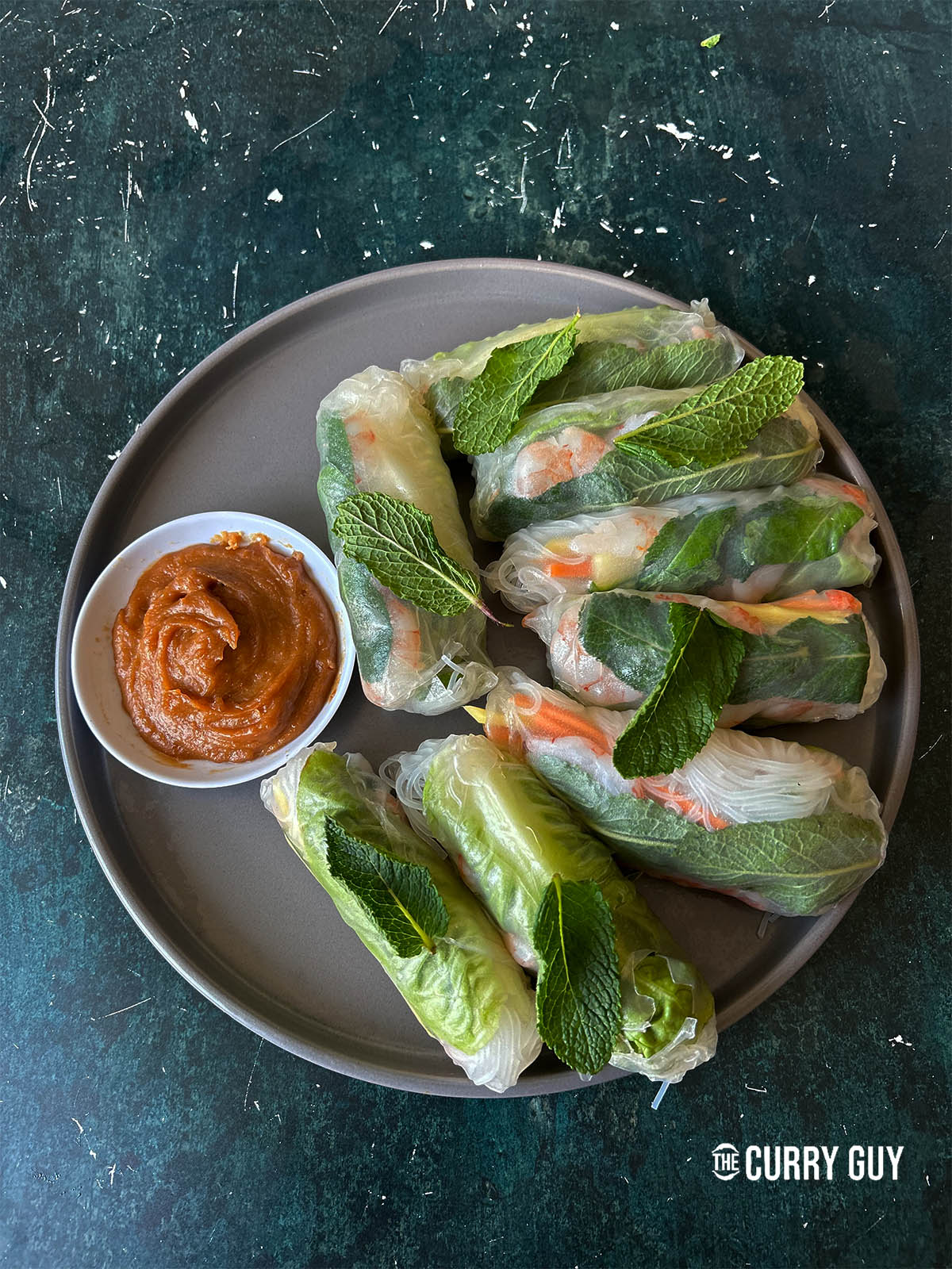 Summer rolls on a plate with peanut dipping sauce.