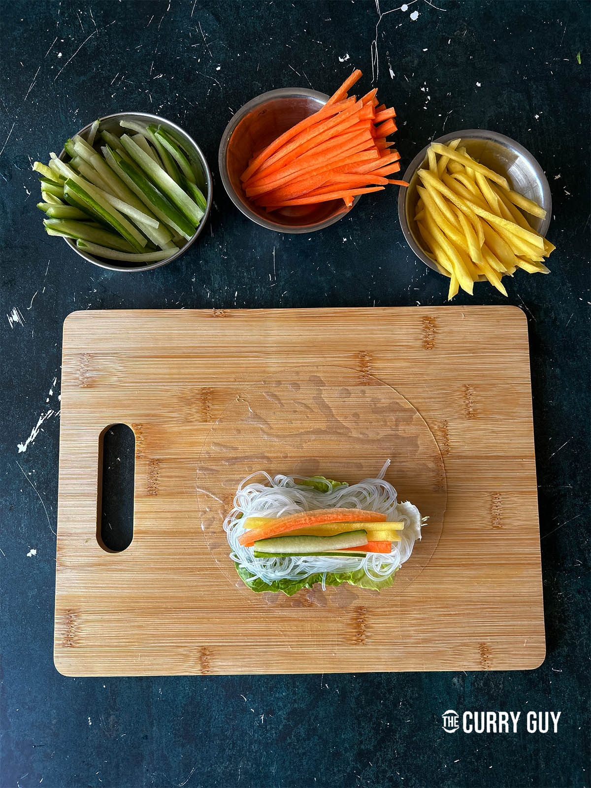 Adding sliced cucumber, carrot and daikon on top of the rice vermicelli noodles.
