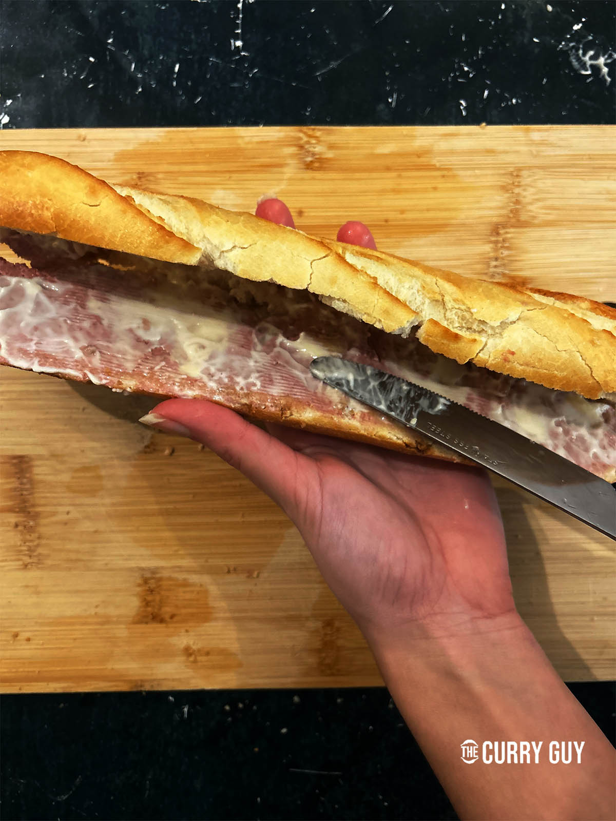 Spreading pate and mayonnaise over the bottom half of the baguette.