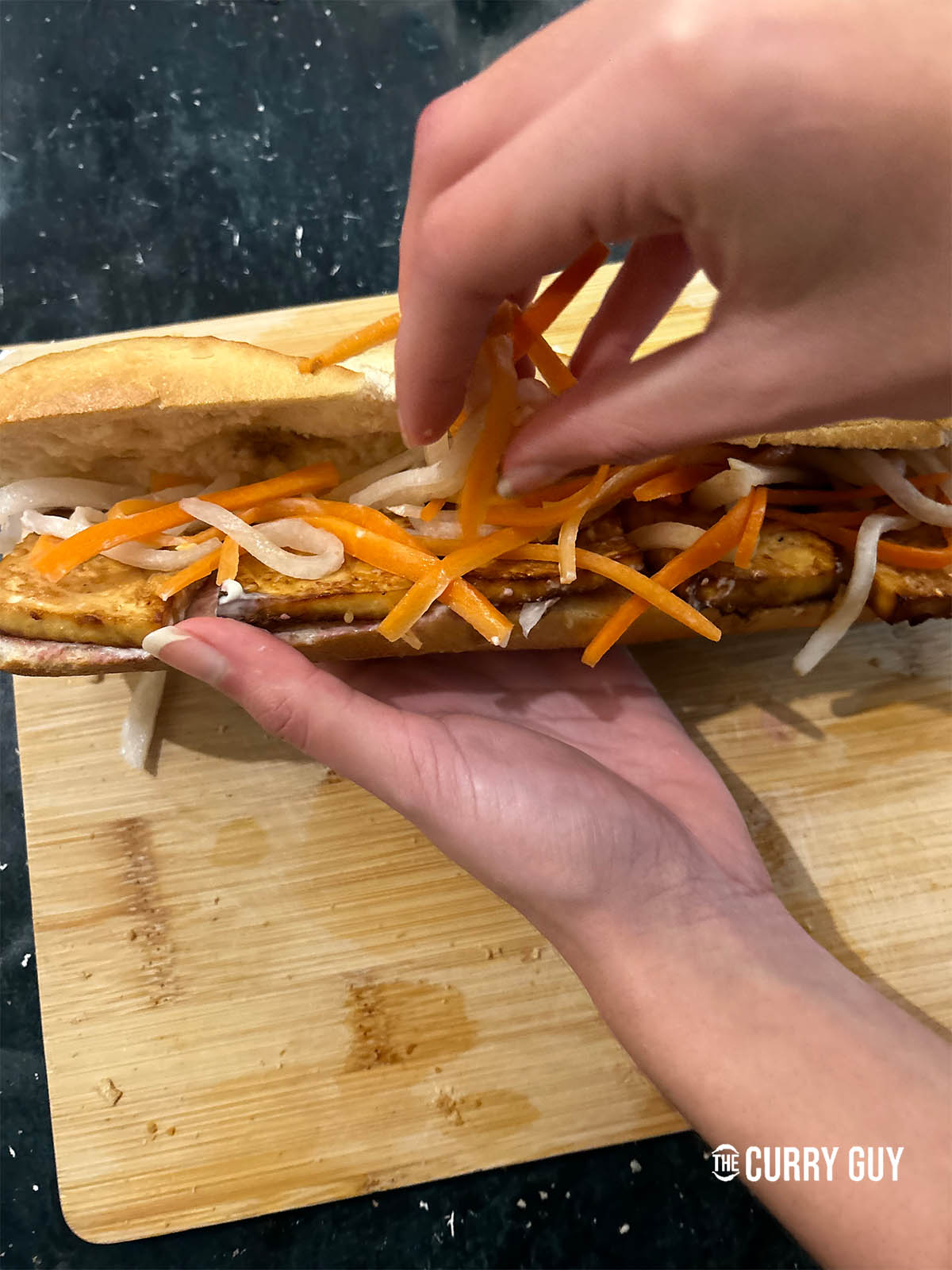 Adding Vietnamese pickled carrots and daikon on top of the tofu.