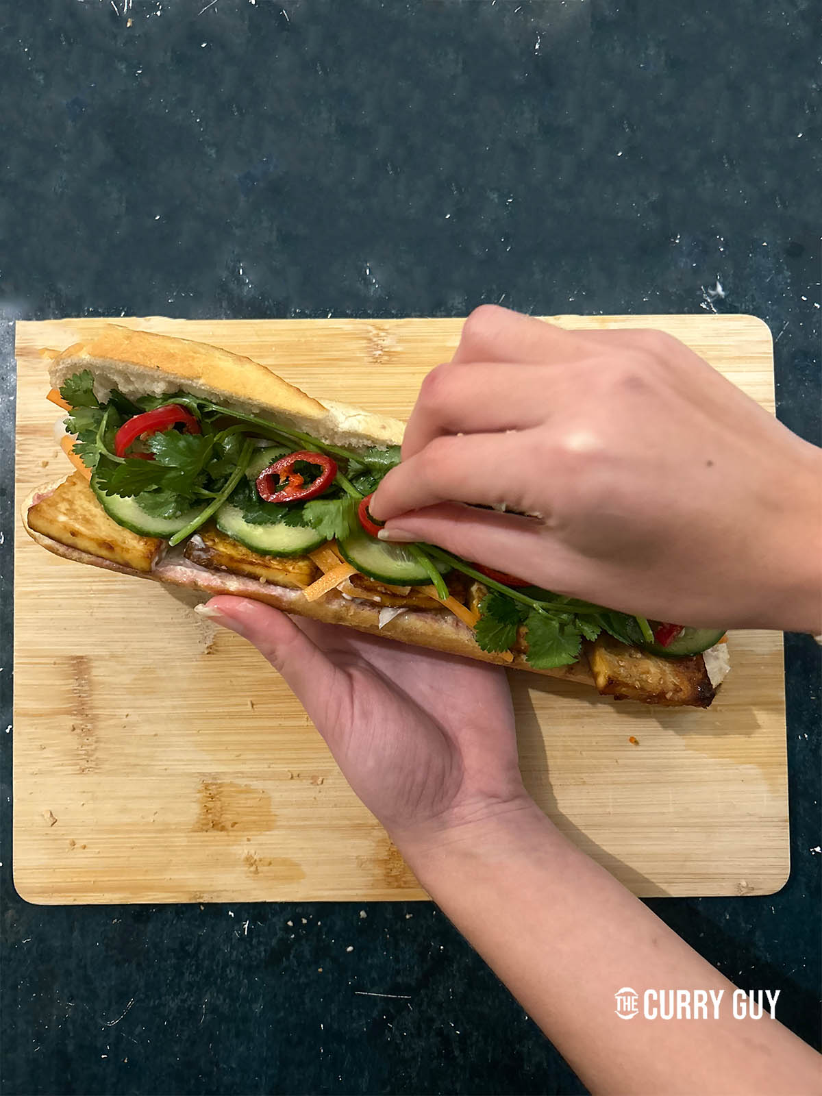Topping the tofu banh mi with vegetables and herbs.