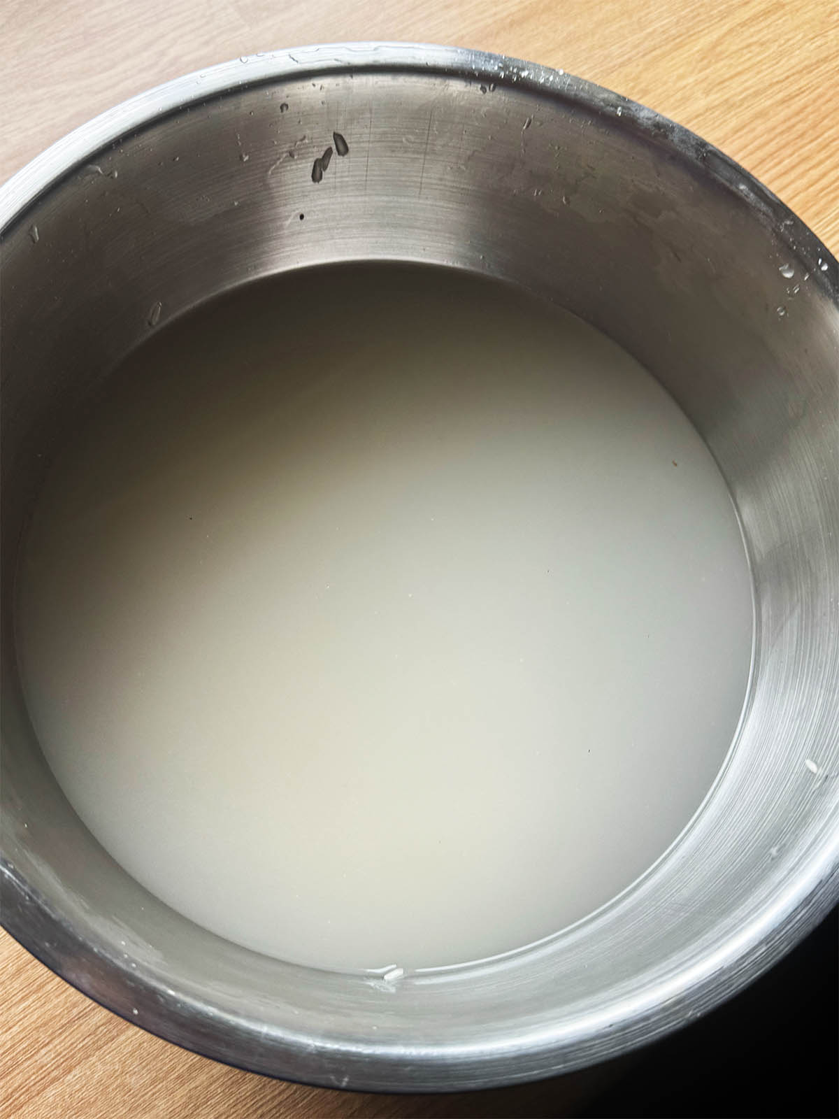 The raw rice in a bowl covered with water that is milky due to the starch.