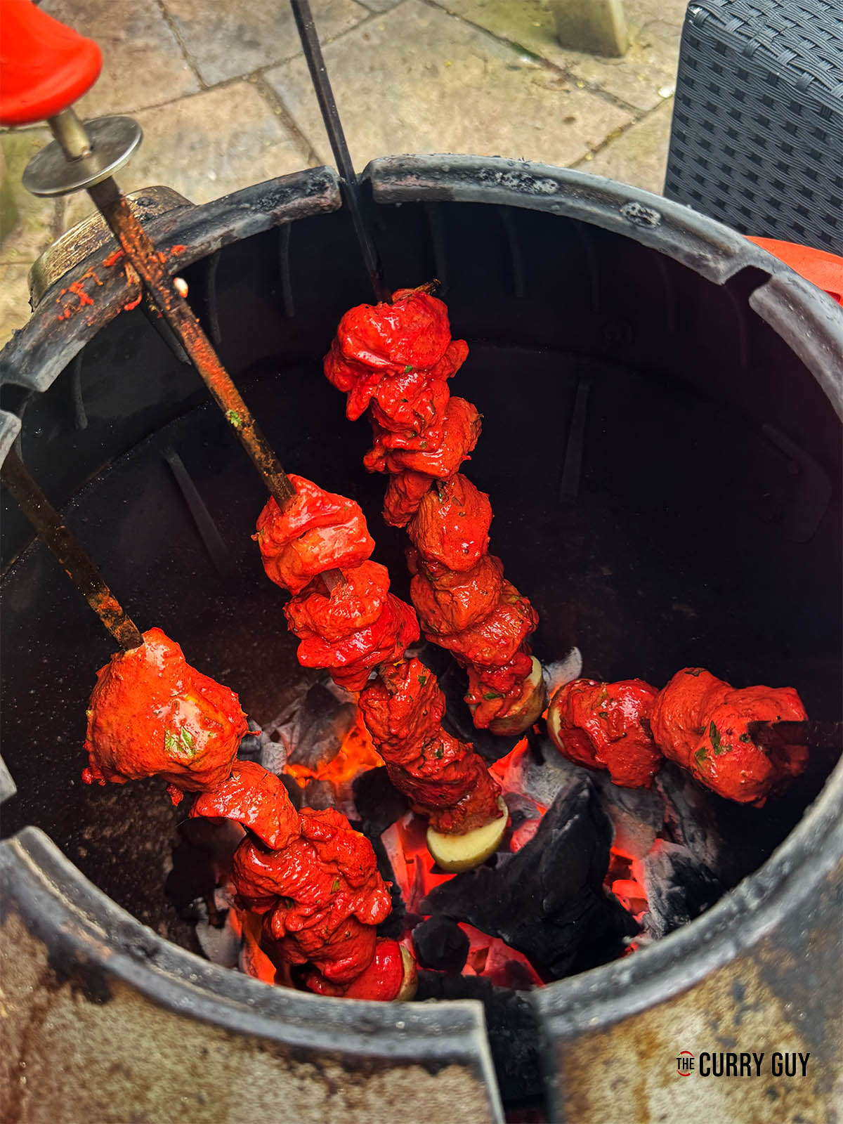 Placing the tandoori chicken skewers in the tandoor oven