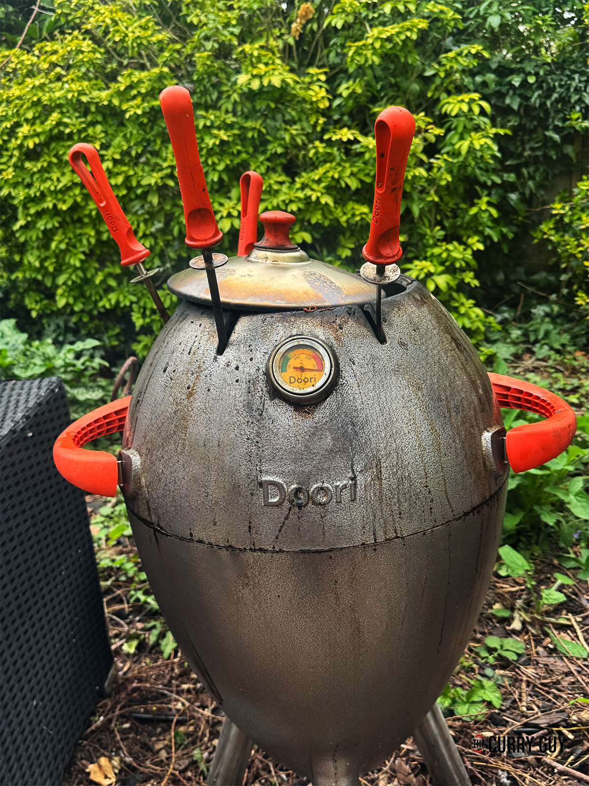 Covering the tandoor to cook the chicken skewers