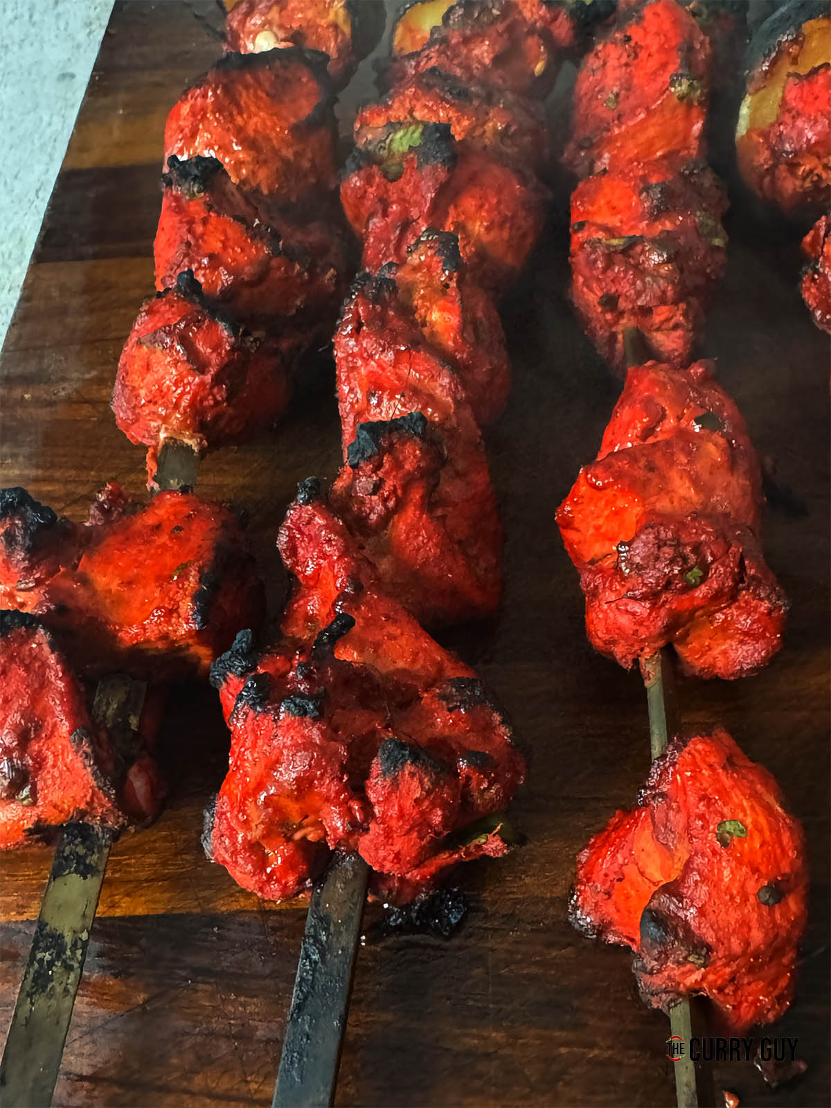 The cooked chicken on skewers on a wooden board.