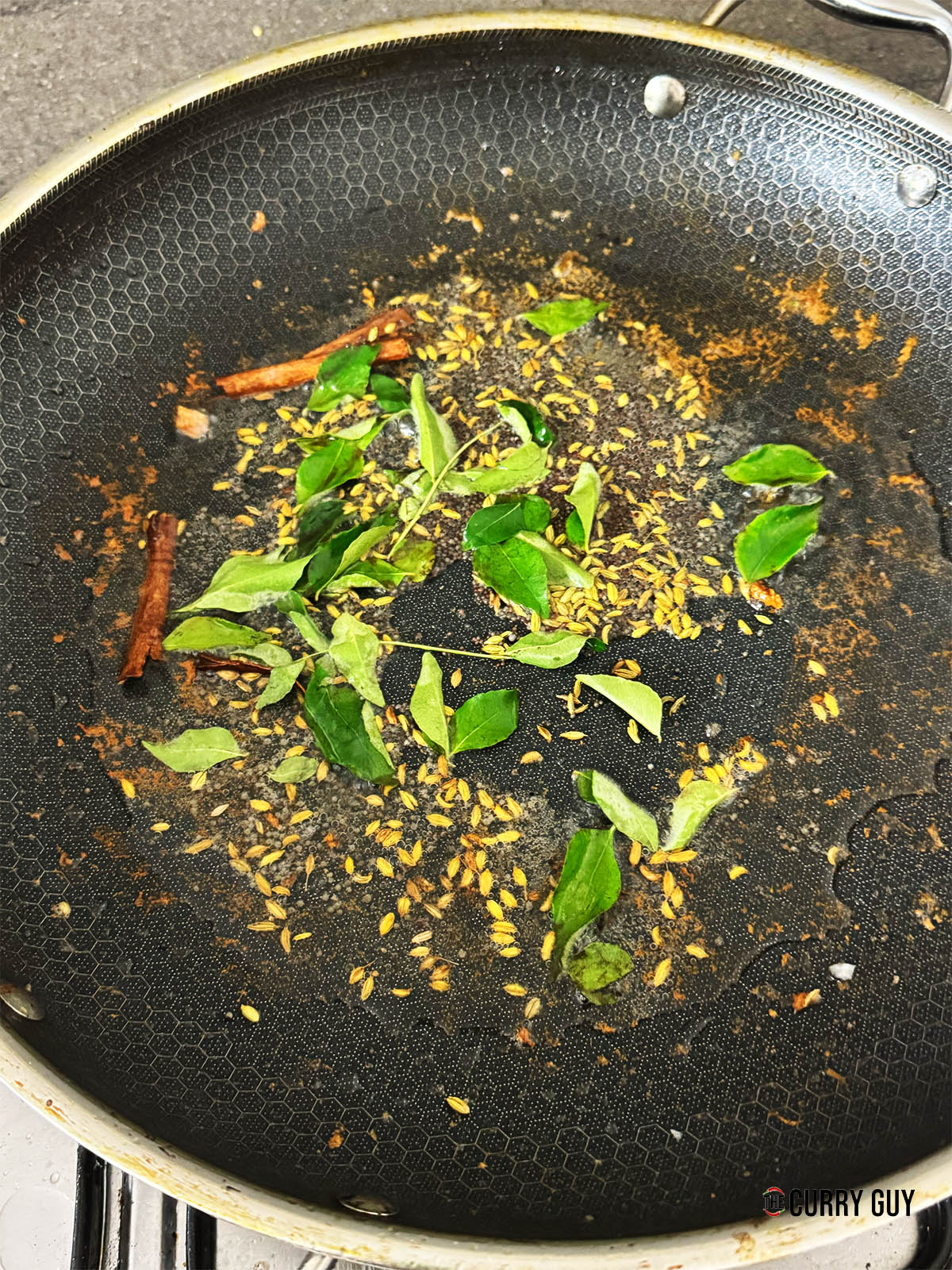 Stirring in the curry leaves to infuse into the oil.