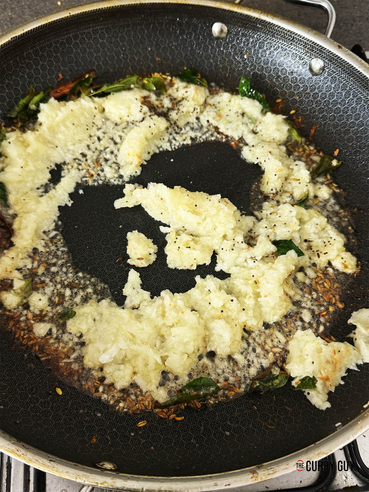 Stirring the blended onions into the pan.