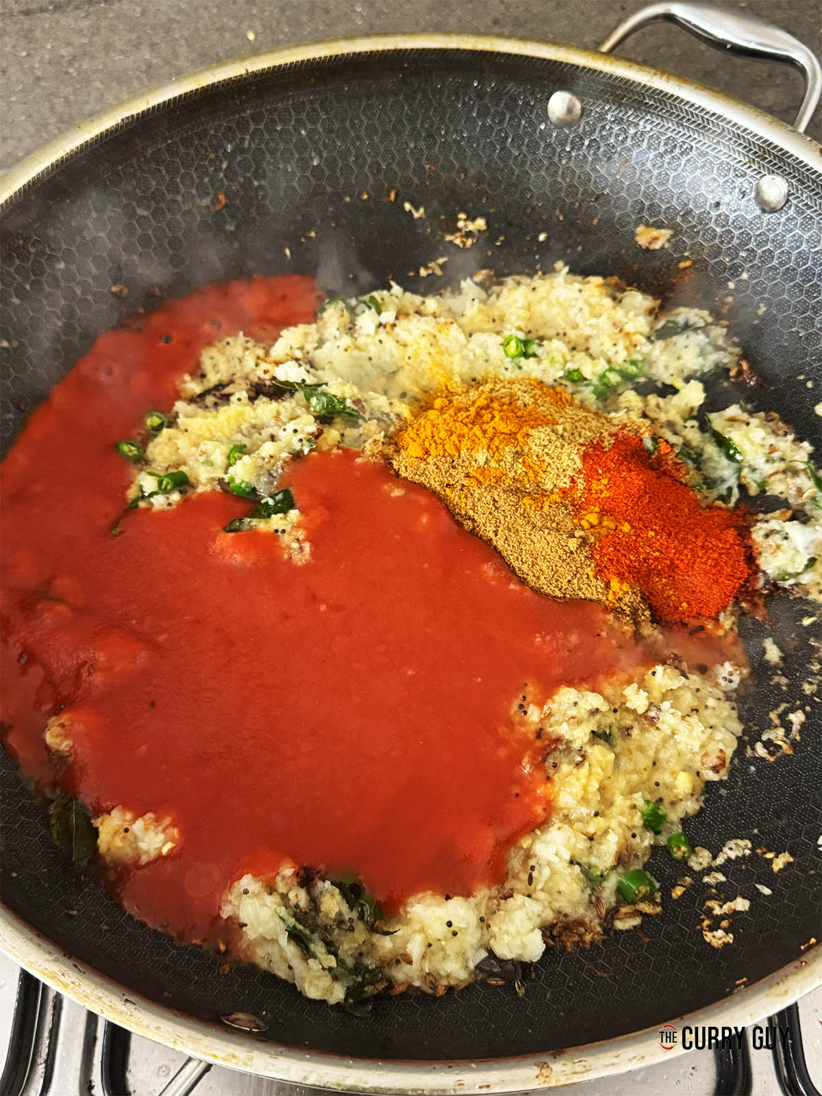 Stirring in the ground coriander, cumin, turmeric and chilli powder along with the passata.