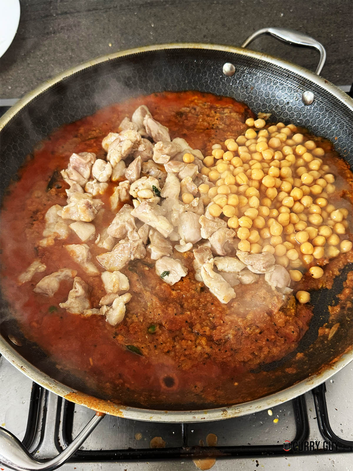 Adding the stock, chicken and chickpeas to the sauce.