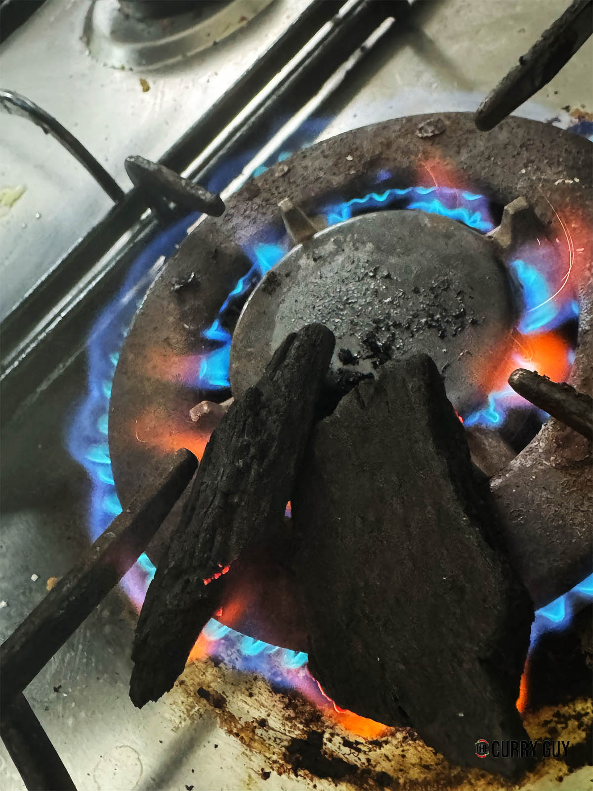Lighting two pieces of charcoal on a gas stove.