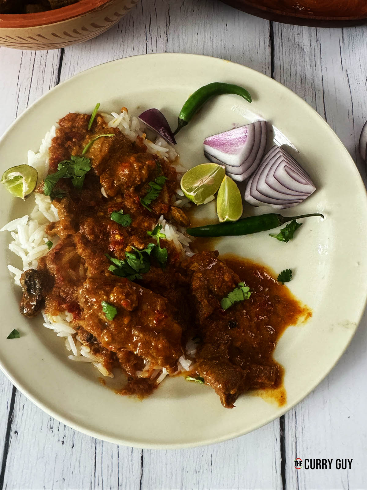 The laal maas on a serving plate over rice.