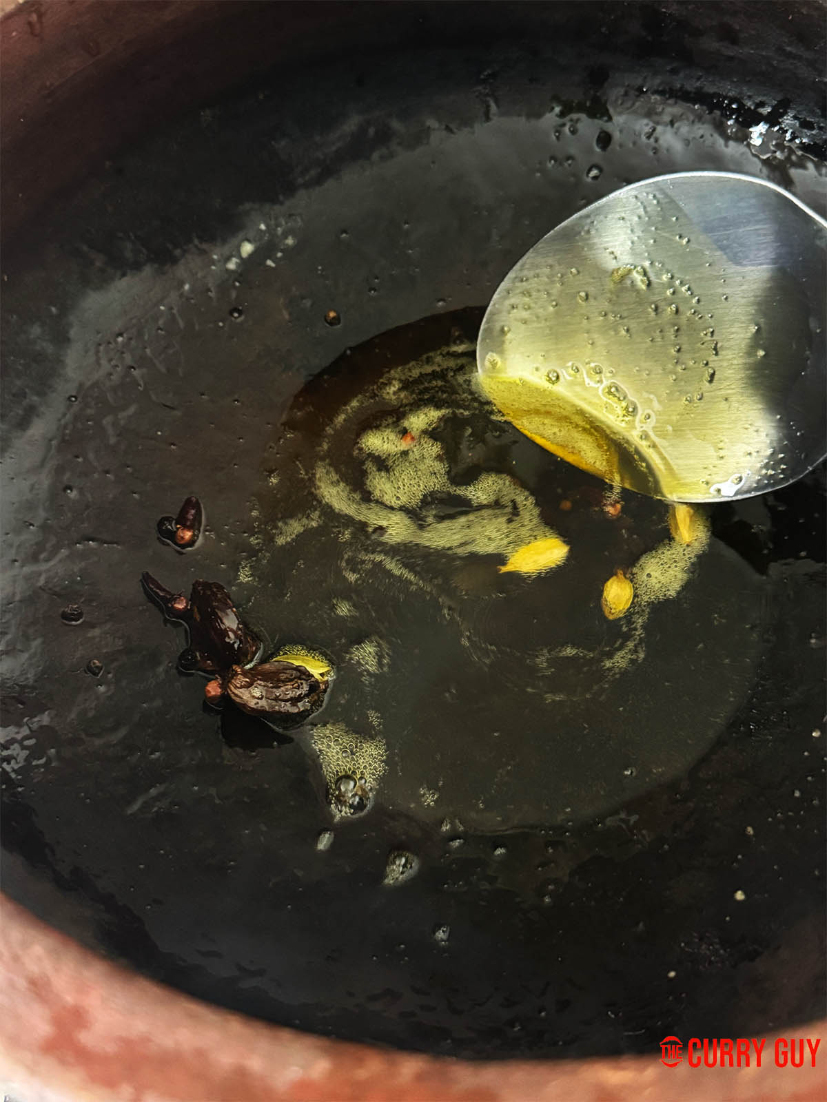 Infusing the cardamom pods, black peppercorns and cloves in mustard oil.