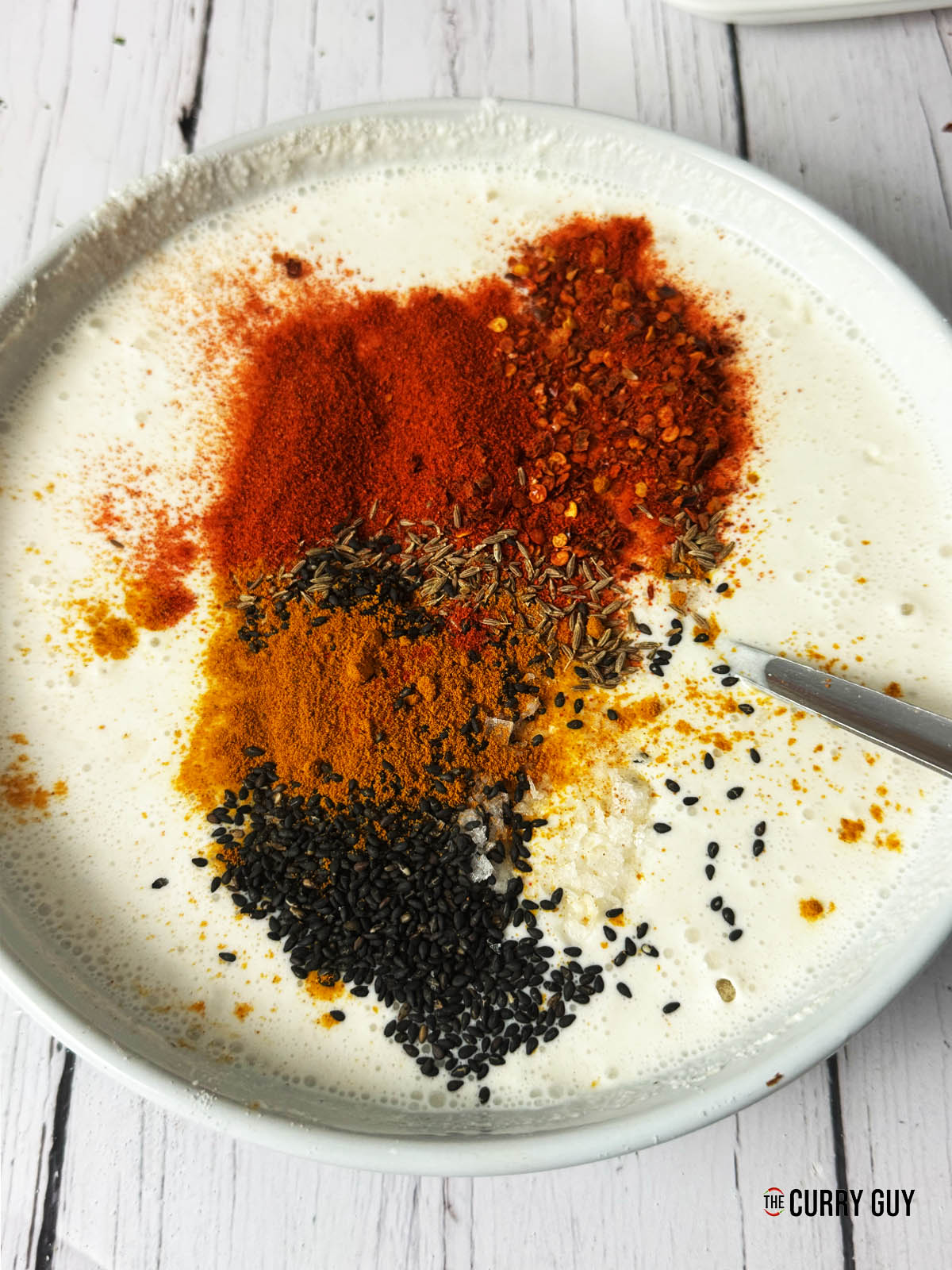 Adding the spices and sesame seeds to the creamy batter.