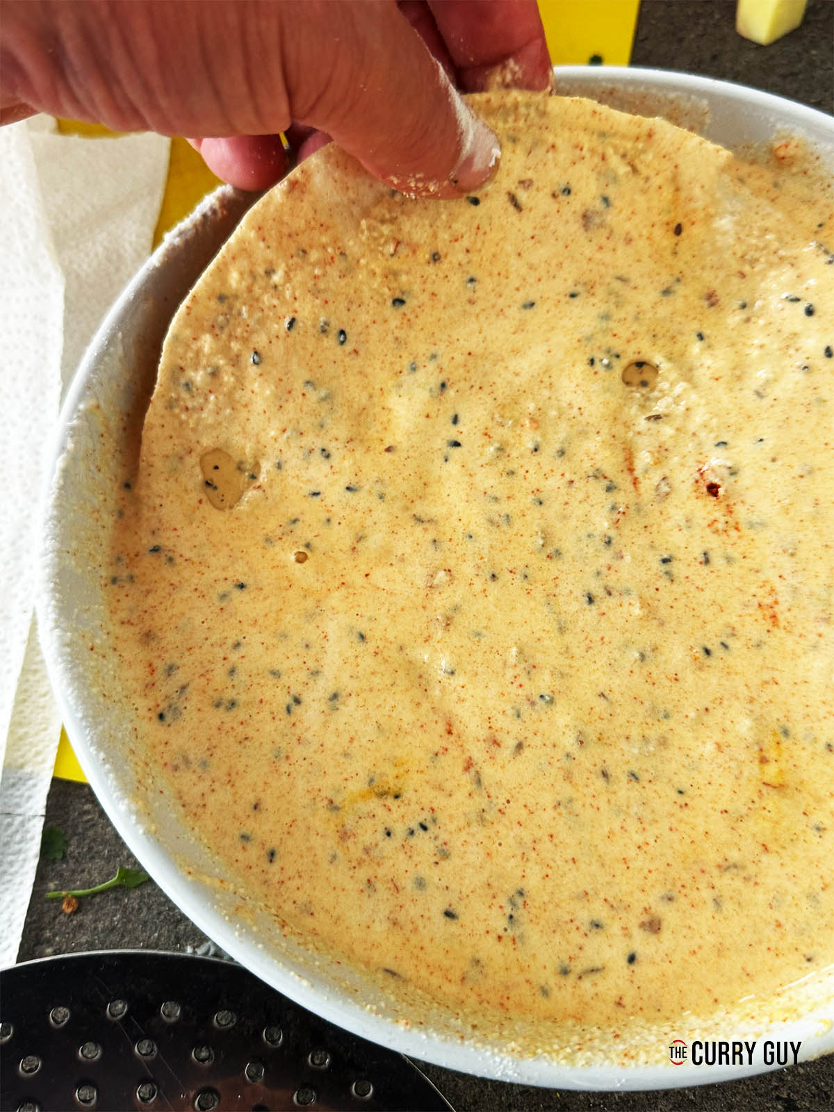 Dipping a papad into the spiced batter.