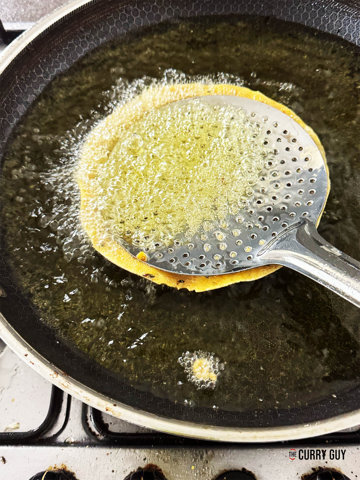 Frying the papad in batter in the hot oil.